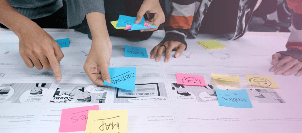 Vue sur plusieurs mains en train de poser des post-its sur un plan d'action